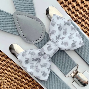 May include: A gray and white bow tie with a bunny rabbit pattern and matching gray suspenders with a leather strap.