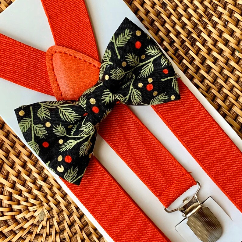 a boy wearing a green bowtie and red suspenders