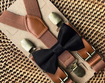 May include: A set of brown elastic suspenders featuring tan faux leather accents and brass-toned metal clips, paired with a solid black bow tie. The items are mounted on a rectangular cardboard display card for presentation and storage.