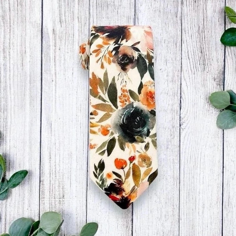 May include: A cream-colored tie with a watercolor floral pattern in shades of orange, green, and blue.