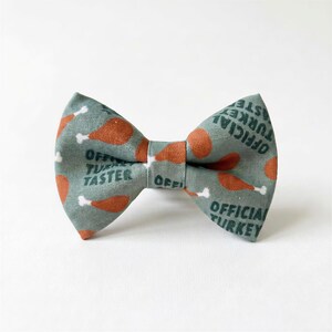 A turkey dog bow tie with a pattern of orange and green turkey images, along with the text "OFFICIAL TURKEY" printed on it.
