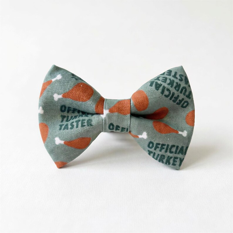 A turkey dog bow tie with a pattern of orange and green turkey images, along with the text "OFFICIAL TURKEY" printed on it.
