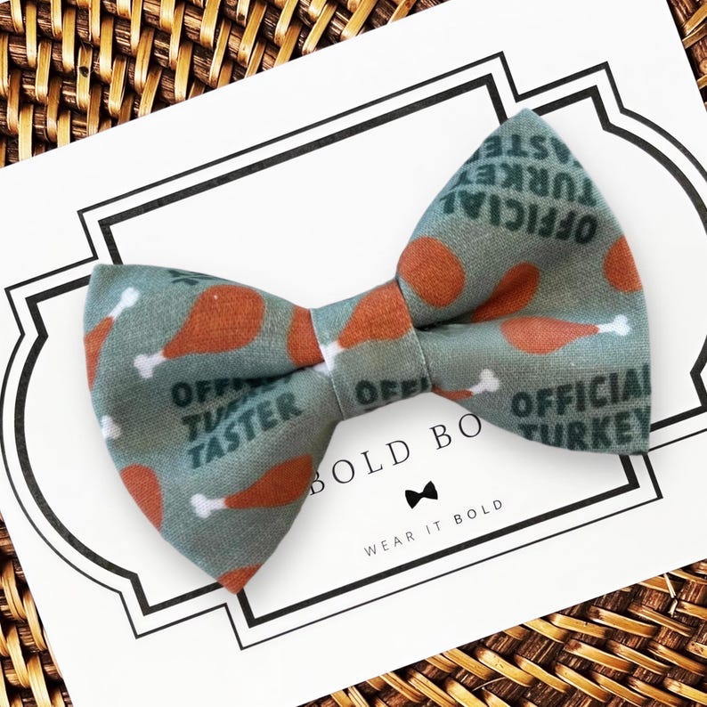 A Thanksgiving dog bow tie with a pattern of orange and green turkey images is displayed on a white card with text.