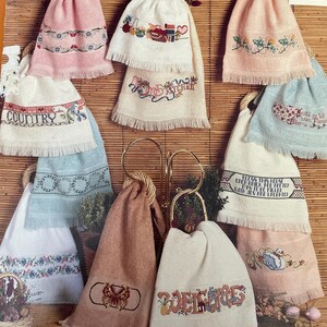 May include: Ten embroidered kitchen towels with fringe, each featuring a different design. The designs include a butterfly, a swan, a heart, a house, a pineapple, a kitchen scene, a country scene, and the words "Bless this home", "Welcome", "Believe", and "Country".