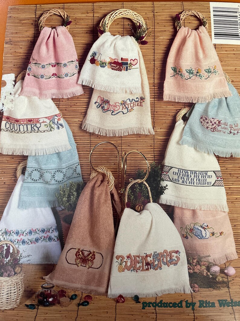 May include: Ten embroidered kitchen towels with fringe, each featuring a different design. The designs include a butterfly, a swan, a heart, a house, a pineapple, a kitchen scene, a country scene, and the words "Bless this home", "Welcome", "Believe", and "Country".