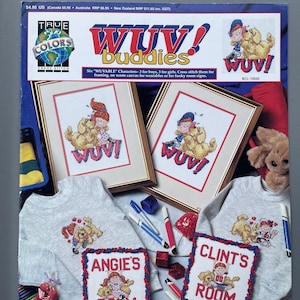 May include: A display of cross-stitch items featuring the "WUV! Buddies" theme. The image includes framed cross-stitch art, sweatshirts, and room signs. The color palette includes red, blue, and gold. The text on the items reads "WUV!" and "Angie's Room" and "Clint's Room".