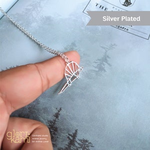 Peut inclure: Collier en argent plaqu&eacute; avec un pendentif en forme d'armadillo g&eacute;om&eacute;trique de style origami. Le pendentif est en argent et a une finition brillante. Le collier est sur une cha&icirc;ne en argent.