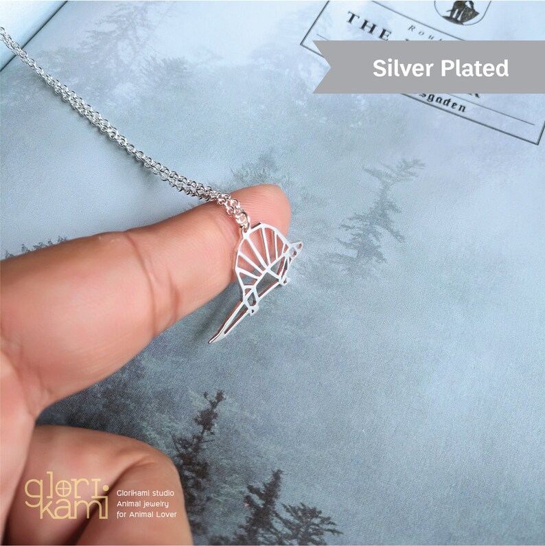 Peut inclure: Collier en argent plaqu&eacute; avec un pendentif en forme d'armadillo g&eacute;om&eacute;trique de style origami. Le pendentif est en argent et a une finition brillante. Le collier est sur une cha&icirc;ne en argent.