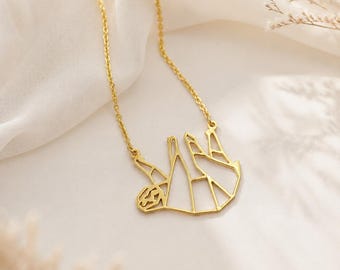 Peut inclure: Un collier doré avec un pendentif géométrique en forme de paresseux, conçu dans un style filaire. Le pendentif est suspendu à une fine chaîne dorée assortie, mettant en valeur des lignes épurées et une structure angulaire ouverte.