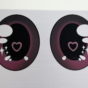 Puede incluir: Dos diseños de ojos estilo anime. Cada ojo es de color burdeos oscuro con una pupila negra, un reflejo blanco y un corazón rosa en el centro. También se incluyen explosiones de estrellas blancas y pequeños puntos blancos en el diseño.