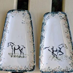 May include: Two rectangular serving trays with a white background and a black horse illustration. The trays have a speckled border with blue trim. One horse is standing, and the other is running.