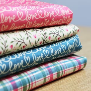 Peut inclure: Un empilement de quatre carrés de tissu avec des motifs différents. Le carré du dessus est rose avec une inscription cursive blanche qui dit "love". Le deuxième carré est blanc avec des branches brunes et des cœurs roses. Le troisième carré est bleu avec une inscription cursive blanche qui dit "love". Le carré du bas est un tissu à carreaux bleu et rose.