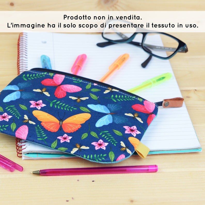 May include: A blue zippered pouch with a butterfly and bee print. The pouch is lying on top of a notebook and a pair of glasses.