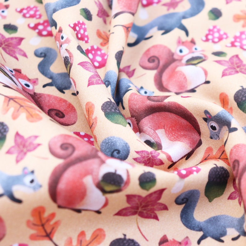 May include: A beige fabric with a repeating pattern of squirrels, acorns, and leaves. The squirrels are red and brown with bushy tails. The leaves are in shades of red, orange, and yellow. The acorns are brown.