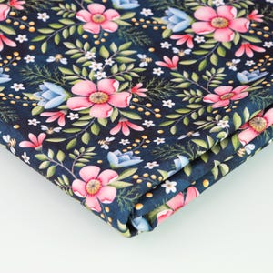 Puede incluir: Una tela azul oscuro con un patrón floral. La tela presenta flores rosas y blancas con hojas verdes y detalles amarillos.