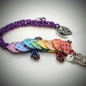 May include: A rainbow dragon scale bracelet with a purple chain and a silver dragon head charm. The scales are made of metal and have a white and gray pattern.