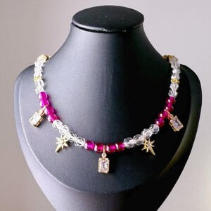 May include: A pink and clear crystal beaded necklace with gold star and square charms.