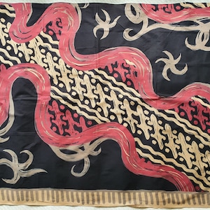 以下が含まれることがあります： 赤、ベージュ、金色の抽象的な形が繰り返される模様の黒い織物。デザインには波線と様式化された花の要素が含まれています。端はベージュのボーダーで仕上げられています。