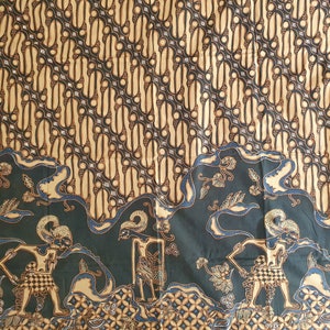 Op de afbeelding: Een stoffen patroon met een herhalend ontwerp van zwarte en beige vormen. De onderste rand heeft een donkergroene rand met figuren en bloemmotieven in beige en blauw. De stof heeft een traditionele, culturele esthetiek.