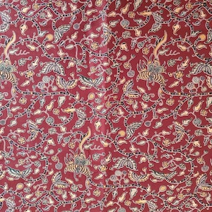 以下が含まれることがあります： ブルゴーニュ色の生地に、様式化された花柄と鳥のようなモチーフが繰り返されています。デザインは、クリーム、黄色、緑の色合いで、渦巻くツル、葉、小さな花が特徴です。全体的な効果は、詳細で装飾的なテキスタイルです。
