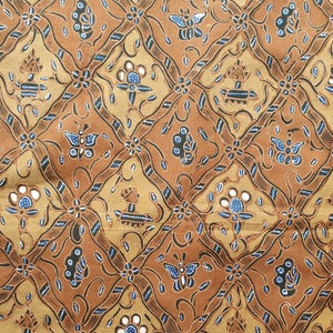 May include: Close-up of a brown and tan batik fabric with a repeating pattern. The design features diamond shapes with floral and butterfly motifs, connected by dark brown lines with blue accents. The fabric has a textured appearance.