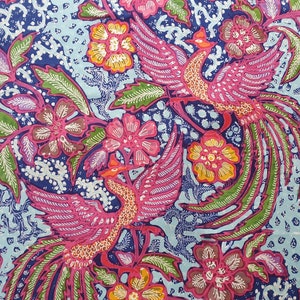 May include: A patterned textile featuring two stylised phoenixes in pink and orange, surrounded by pink and yellow flowers and green leaves. The background is a mix of blue and light blue with white dots.