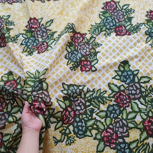 Könnte beinhalten: Blumenstoff mit einem sich wiederholenden Muster aus roten, grünen und blauen Blumen auf gelb-weißem Hintergrund. Der Stoff hat ein gitterartiges Muster und wird wahrscheinlich für Textilien oder Heimdekoration verwendet.