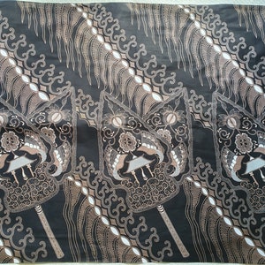 Puede incluir: Una tela negra con un patrón batik marrón y blanco. El diseño incluye formas estilizadas en forma de abanico y motivos florales. La tela tiene un patrón diagonal con elementos repetidos.