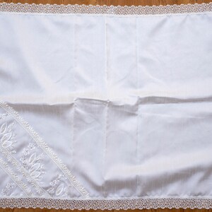 May include: White prayer rug with a delicate lace border and embroidered floral designs.