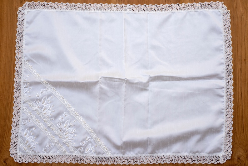 May include: White prayer rug with a delicate lace border and embroidered floral designs.