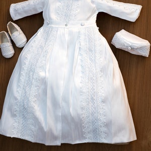 Detachable baptism robe for a boy with white long sleeves, with fine embroidered details, with high quality fabric to provide comfort to the baby. He has a hat that matches the baptismal robe.