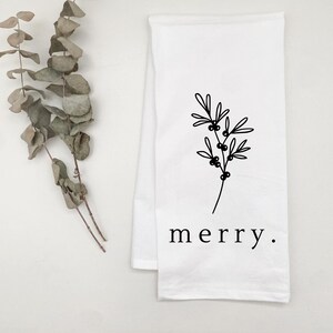 May include: White kitchen towel with a black line drawing of a sprig of holly and the word "merry".