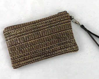 May include: A rectangular woven clutch in shades of brown and beige, featuring a zipper closure and a wrist strap. The clutch has a textured appearance and a silver-tone metal clasp.
