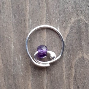 Earring with amethyst bead on a wooden background.