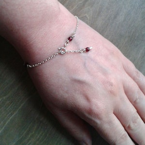 Garnet bracelet on a wrist. The part of the chain that hangs when the bracelet is closed is completed by a garnet bead.