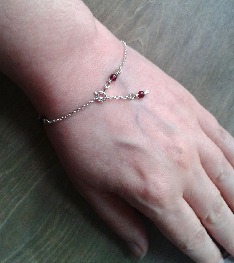 Garnet bracelet on a wrist. The part of the chain that hangs when the bracelet is closed is completed by a garnet bead.