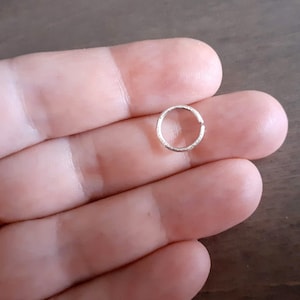 Brilliant hoop earring held by a hand.