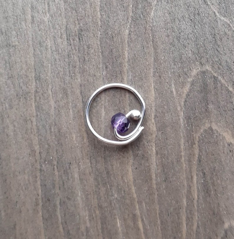 Earring with amethyst bead on a wooden background.