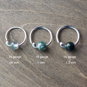 Three sterling silver hoops with bead of moss agate on wooden background. Gauge dimensions are added (please, find them in the description section of this listing).