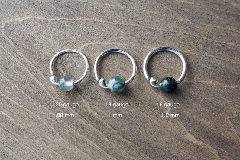 Three sterling silver hoops with bead of moss agate on wooden background. Gauge dimensions are added (please, find them in the description section of this listing).