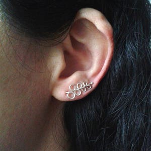 May include: Silver ear cuff with a delicate, leaf-like design featuring multiple small circles.