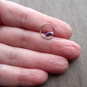 Earring with amethyst bead on a hand.