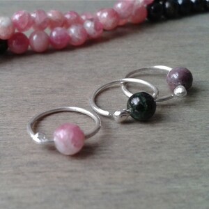 Tourmaline hoops against a wooden background.