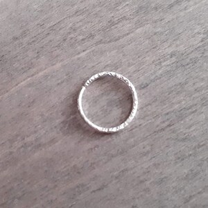 Brilliant hoop earring in sterling silver against a wooden background.