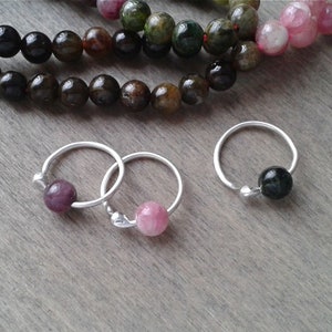 Tourmaline hoops against a wooden background. These hoops are offered with beads of various colors that you will be able to choose when adding them to your cart.