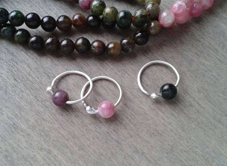 Tourmaline hoops against a wooden background. These hoops are offered with beads of various colors that you will be able to choose when adding them to your cart.