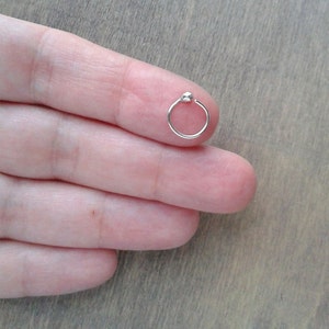 A hoop pictured on a fingertip. The hoop is offered in many gauges and diameters. Please, choose the one that best fits your piercing at checkout.