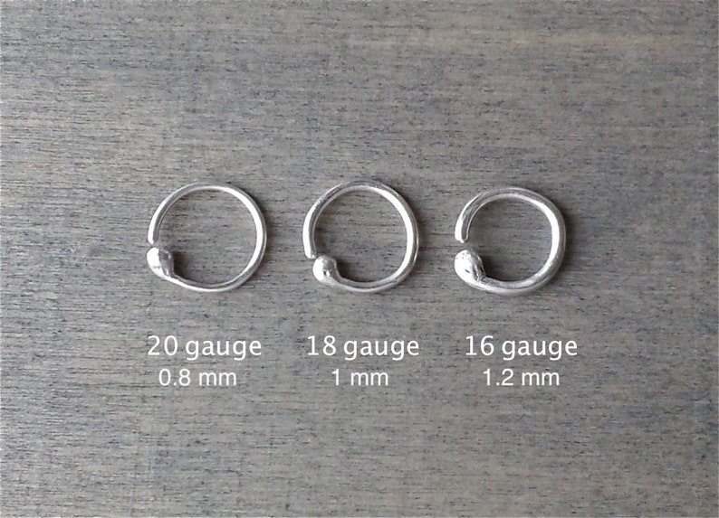 3 sterling silver hoops against a wooden background. They are is 3 different gauges (thicknesses): the 20 gauge hoop is 0.8 mm thick; the 18 gauge hoop is 1 mm thick; the 16 gauge hoop is 1.2 mm thick.