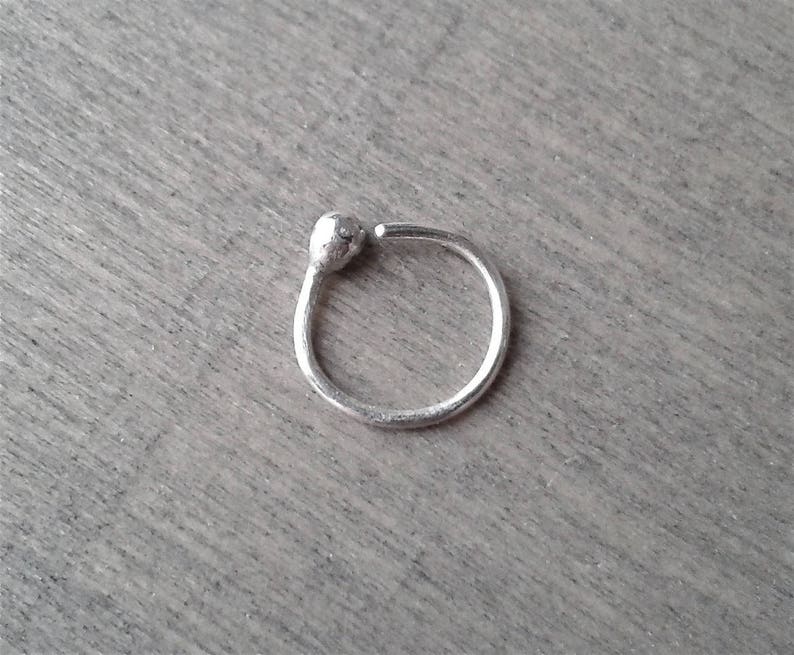 Sterling silver hoop against a wooden background. One end of the hoop has been worked with a torch to form a rounded ball.