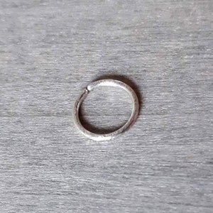 Brilliant hoop earring in sterling silver against a wooden background.